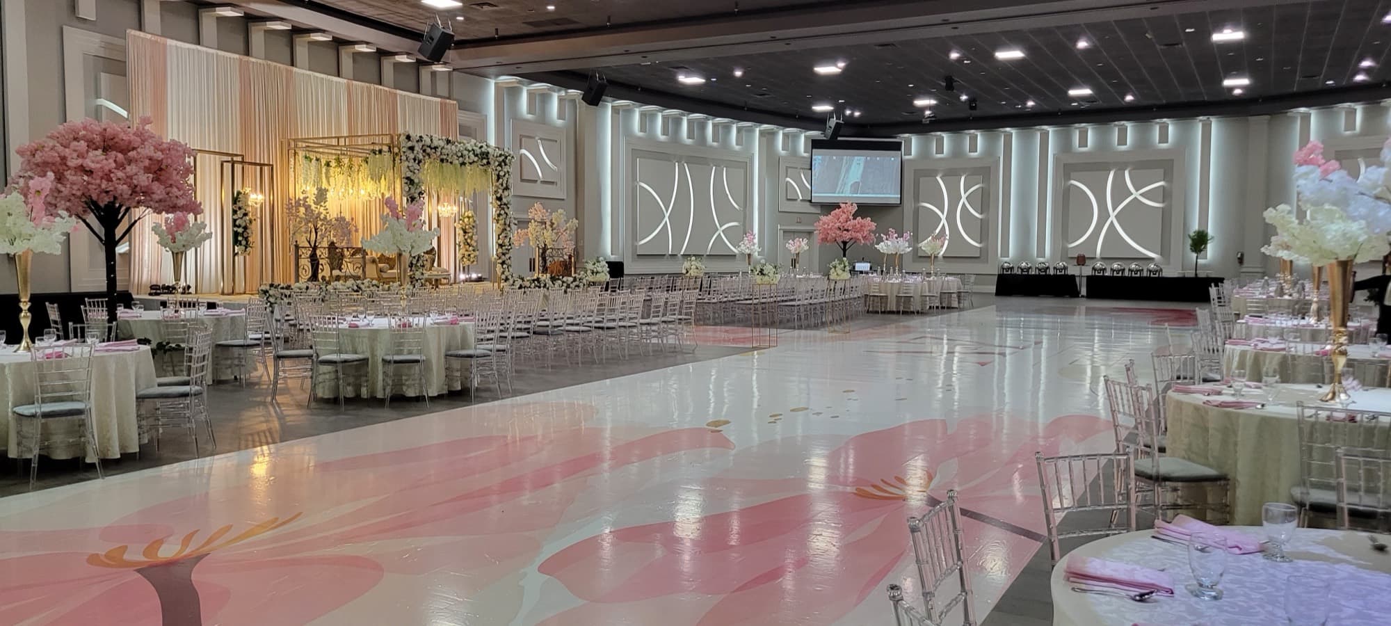 Ballroom at Palacio Event Centre with a custom printed floral dance floor, blossom trees and a gold floral stage backdrop