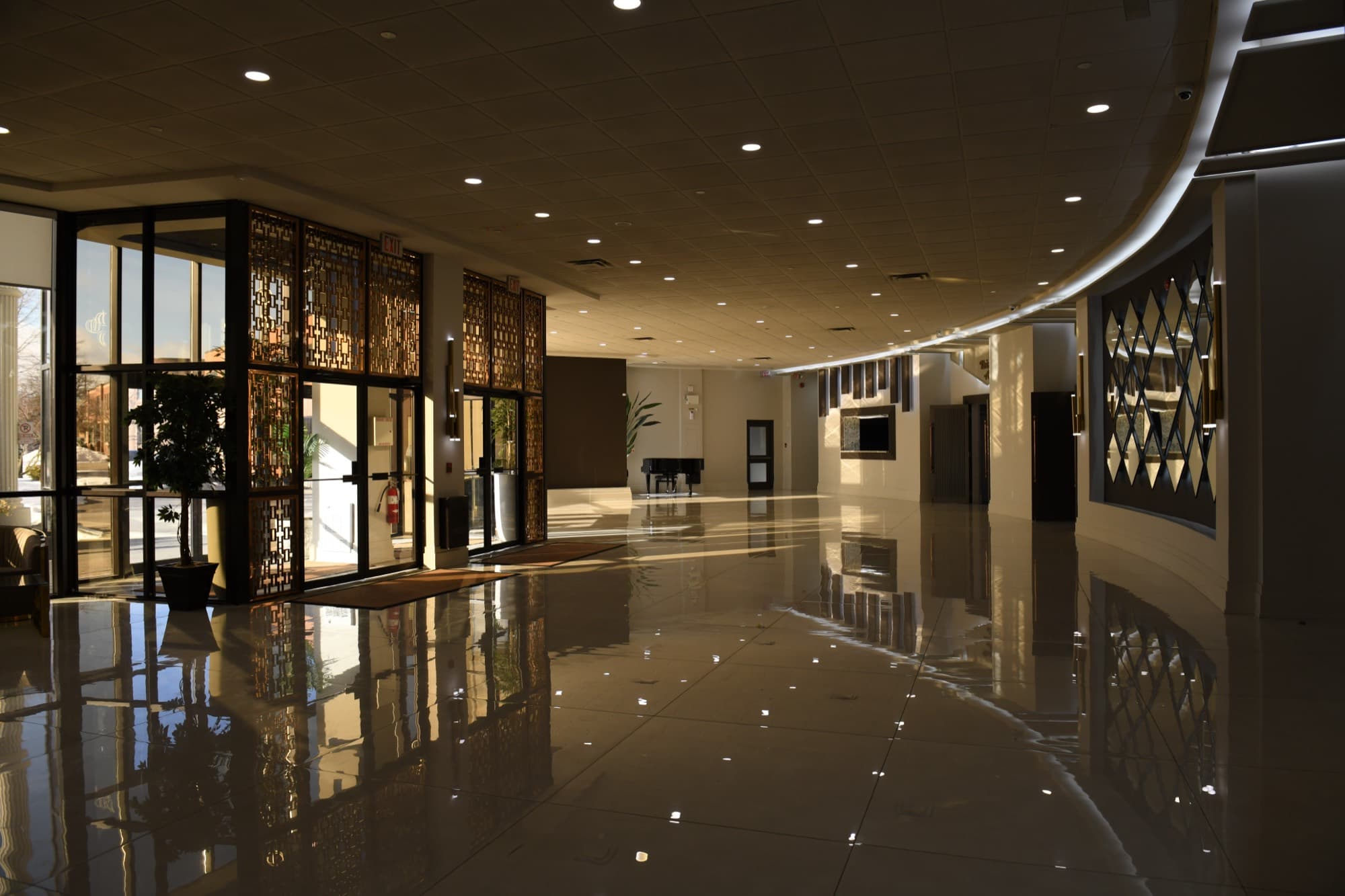 Sunlight across the polished lobby floor at Palacio Event Centre, with decorative metal screens and a grand piano beyond