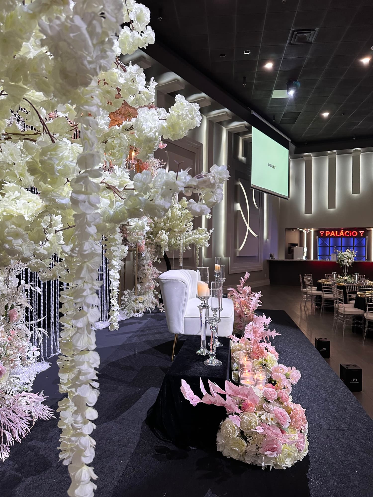 Candlelit top table with florals and crystal candelabras in front of the illuminated Palacio Event Centre sign