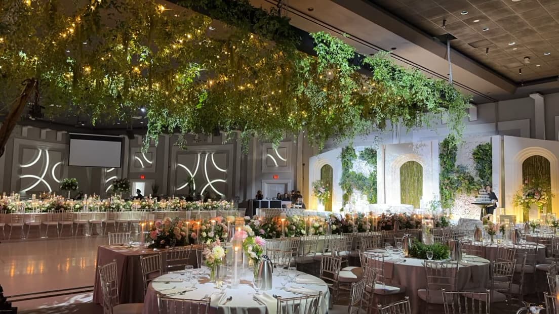 Ibiza Grand Ballroom at Palacio Event Centre dressed with a suspended greenery canopy, long candlelit head tables and a floral stage backdrop